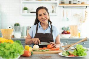A woman cutting a variety of vegetables in a bright kitchen space