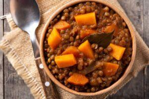 Top view of a bowl of lentil stew topped with pumpkin
