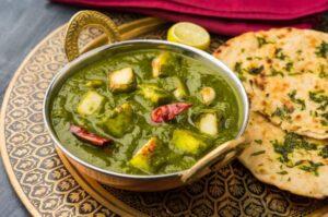 A bowl of palak paneer served with roti on the side