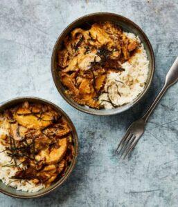 A bowl of rice topped with vegetarian rendang sitting on a granite counter