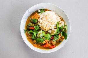 Top view of a bowl of vegan curry with rice in a white bowl