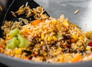 Fried rice being stirred in a wok using a spatula