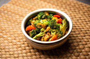 A bowl of stir-fried mixed vegetables on a wooden surface